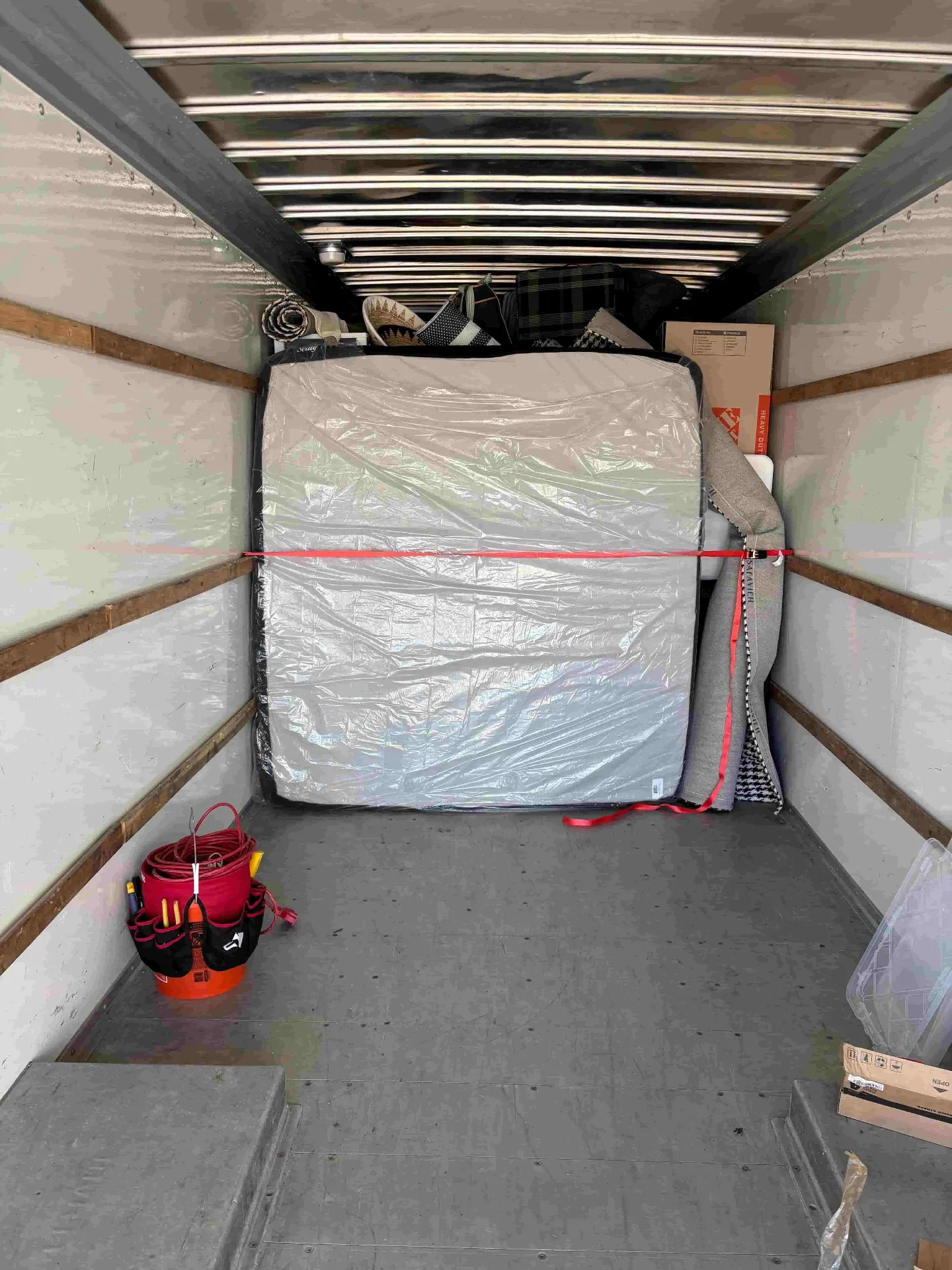 Mattress wrapped and strapped securely by movers inside a truck — professional load building